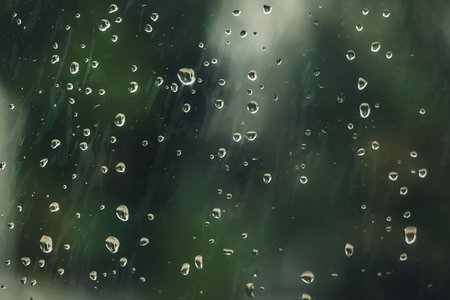 Raindrops on misted glass close-up, abstract green background