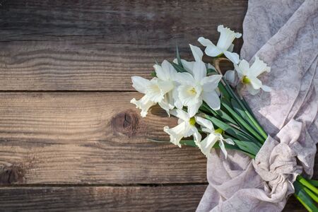 A bouquet of beautiful white and yellow daffodils on a rustic wooden background close up, with a copy spaceの写真素材