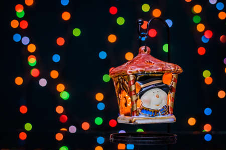 New year's lantern candle holder on the background of colorful bokeh from the Christmas holiday illuminationの写真素材