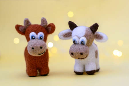 Symbol of 2021, a toy felt brown bulls on a festive light yellow background with bokeh, with a copy spaceの写真素材