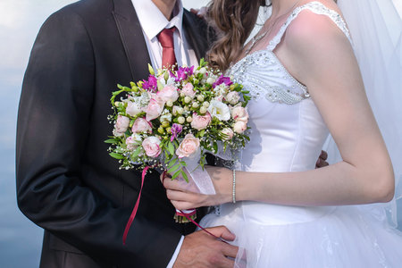 Beautiful wedding bouquet of pink roses in the hands of the bride and groom close-up