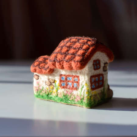 Cute woolen house with windows, tiled roof, flowers, wool feltingの写真素材