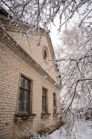 Winter view of an old brick house through snow-covered branchesの写真素材