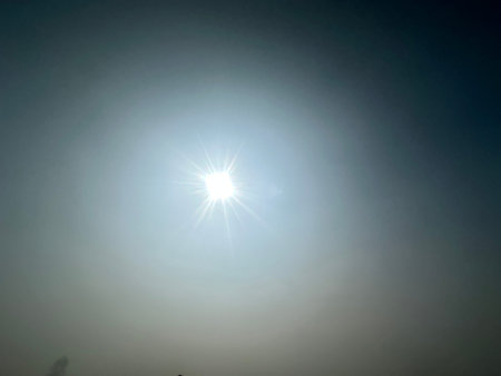 Brilliant sun peeks through overcast sky. Sun illuminating hazy atmosphere with bright light rays...