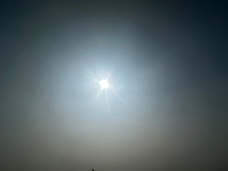 Sun lens flare creating light with clear blue sky. Sun glows on clear sunny day. Optical lens flare with sun in background.の写真素材