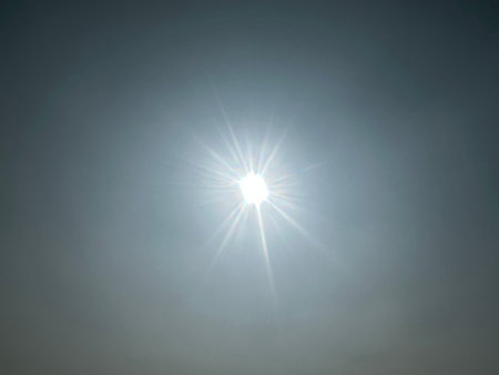 Bright sun radiating light with sunbeams and lens flares creating sunscape. Sun shining creating shimmering rays. Light radiating.の写真素材