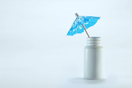 taking a Sick leave  paid sick days  sick pay  a blue paper cocktail umbrella on a white pill box  pill caneの写真素材