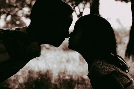 silouette of boy and girl outdoors with noses touchingの写真素材