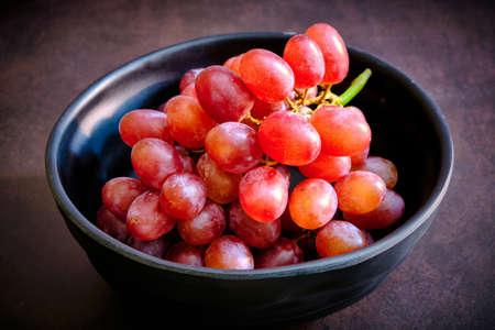 Red delicious fresh grapes on a black bowl. ready to eatの写真素材