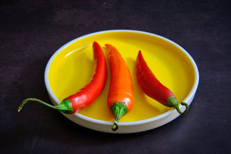 Red chilli pepper on yellow plate in dark background
