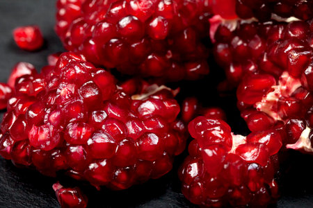 Grains of ripe juicy pomegranate on a black background. Close-up