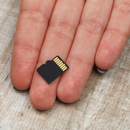 Memory cards on the palm of a young girl on a wooden table. Studio lighting. Close-up.