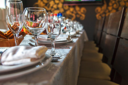 Serving of a festive table with a glass of wine glasses and a glass, and also plates with napkins on...