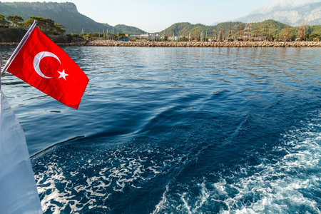 A red Turkish flag with a white crescent and a star is developing by the wind against the backdrop...