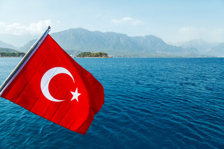 A red Turkish flag with a white crescent and a star is developing by the wind against the backdrop...