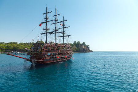 Pleasure pirate ship with tourists sailing in the Mediterranean Sea along the coastline at the foot of the mountainのeditorial素材