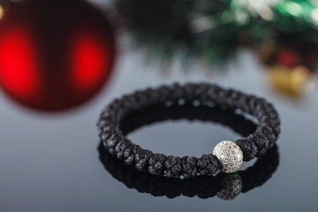 Broyanitsa, woven bracelet made of synthetic thread in which 33 knots and accessories in the form of beads and crosses inlaid with cubic zirconias. Handwork. Close-up. Studio lightingの写真素材