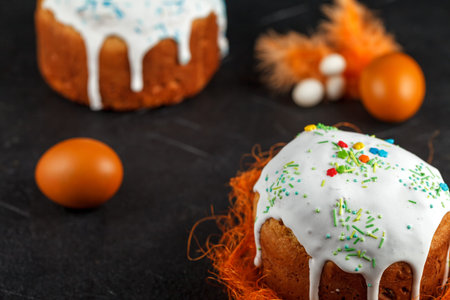 Fresh Easter cake, baked at home and decorated with sweet icing. Colored boiled eggs lie on the...