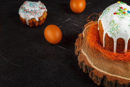 Fresh Easter cake, baked at home and decorated with sweet icing. Colored boiled eggs lie on the...