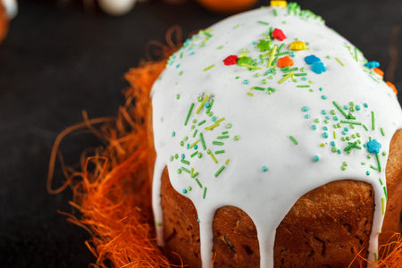 Fresh Easter cake, baked at home and decorated with sweet icing. Colored boiled eggs lie on the...