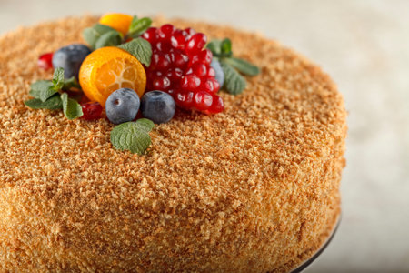 Honey cake with caramel for diabetics decorated with orange, mint, pomegranate slices and...