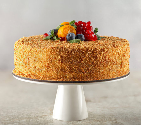 Honey cake with caramel for diabetics decorated with orange, mint, pomegranate slices and...