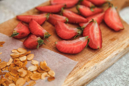 Cutted fresh strawberries and fried almond flakes for decorating and decorating a meringue rollの写真素材
