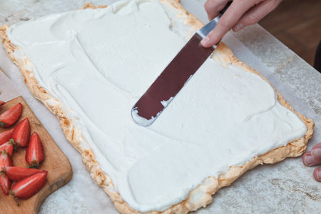 The chief confectioner lubricates the meringue for the roll with a beaten cream.