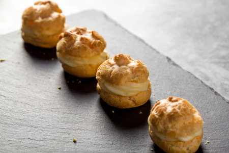 Custard-filled profiteroles ready to serve. The profiteroles are filled with custard and ready to be...