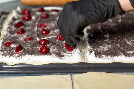 Process making a Napoleon cake with poppy seeds and cherries. Close upの写真素材