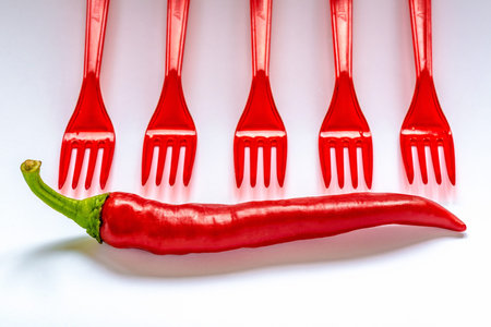Red hot chili peppers with red table forksの写真素材
