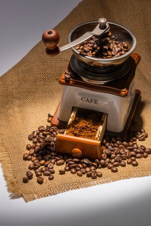 Photo of an antique coffee grinder with coffee beans in the blurred backgroundの写真素材