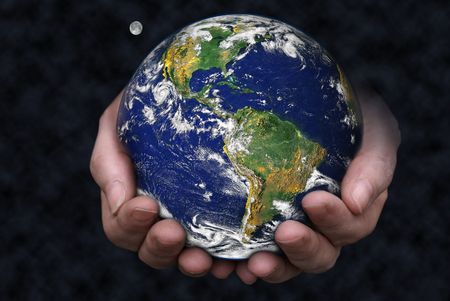 A pair of hands holding the Earth with the moon in the background. の写真素材
