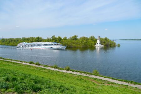 A cruise ship with tourists passes through the Volga-Don Shipping Canal named after Lenin past the lighthouse and goes to the Volga. Volgograd. Russiaの写真素材