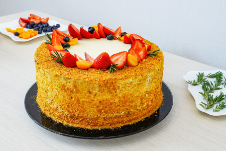 Girl decorates a freshly baked puff cake with fruits and berries: strawberries, blueberries and...