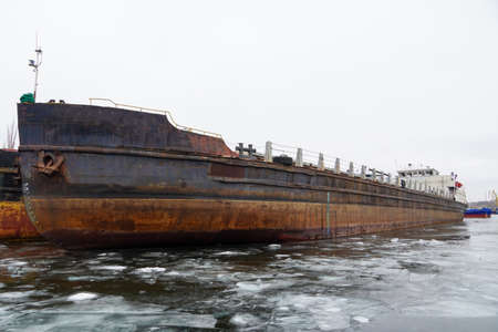An old rusty motor ship is awaiting disposal. Wintering ships on a frozen river in their port. Volgograd. Russiaの写真素材