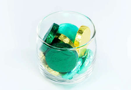 chocolate candy wrapped in colorful foil in a clear glass on white backgroundの写真素材