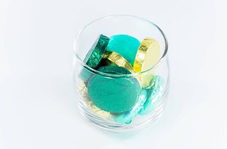 chocolate candy wrapped in colorful foil in a clear glass on white backgroundの写真素材