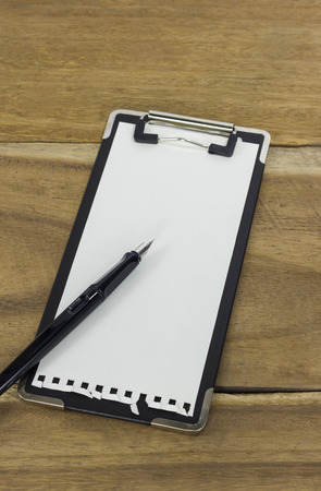 mini clipboard with blank paper and a pen on wooden backgroundの写真素材