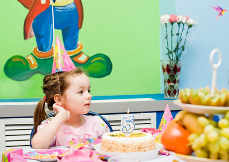The girl at the holiday table  Cake with a candle