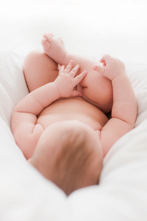 lying naked baby plays with his feetの写真素材