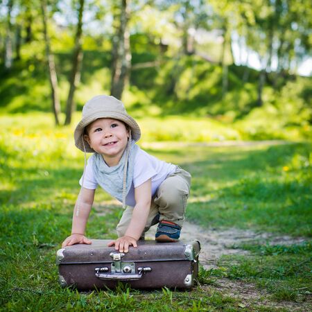 small child in a headdress playfully climbed a suitcaseの写真素材