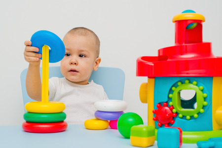 Child collects a pyramid on a table on a white backgroundの写真素材