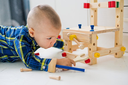 adorable child playing with wooden building toys at homeの写真素材