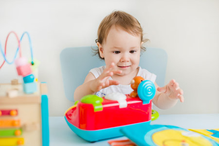baby girl playing with educational toy in nurseryの写真素材