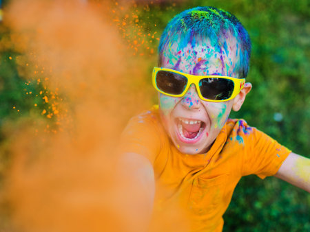 The child in glasses throws paint holi