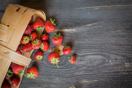 strawberry is scattered from a basket on a wooden backgroundの写真素材