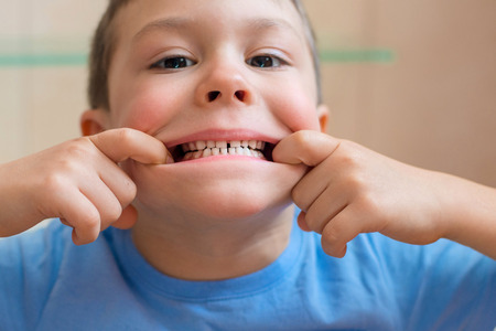 baby stretches her mouth and shows healthy clean teeth in the bathroomの写真素材