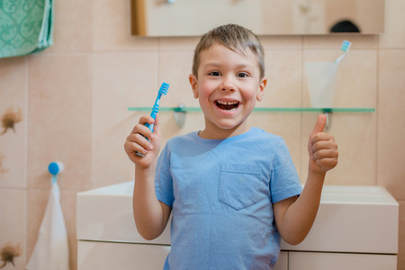Happy kid or child brushing teeth in bathroom. Dental hygiene.の写真素材