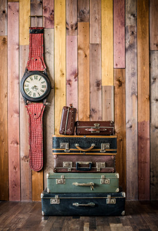 Retro old classic leather suitcases. travel baggage. retro style. Large clock on a wooden backgroundの写真素材